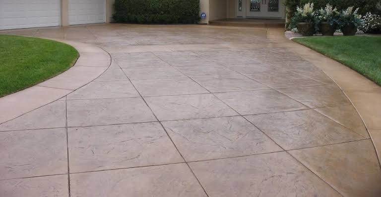 Finished stamped concrete driveway with tile-pattern scoring leading to a home's garage